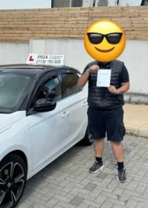 student posing after passing his driving test with his pass certificate in the walthamstow dog stadium car park.