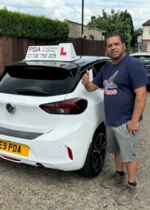 student standing next to a learner driver car giving a thumbs up after completing extra lessons to improve his driving skills.