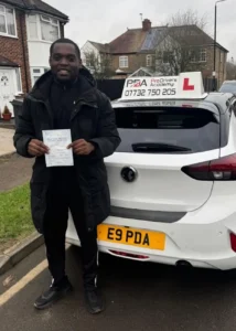 student standing next to learner driver car with his pass certificate near highams park station.