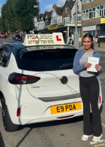 student has passed her driving test and is posing with her test certificate opposite chingford station