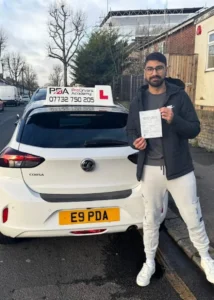 Arayan celebrating his manual driving test pass outside Chingford Test Centre next to the learner car with Pro Drivers Academy
